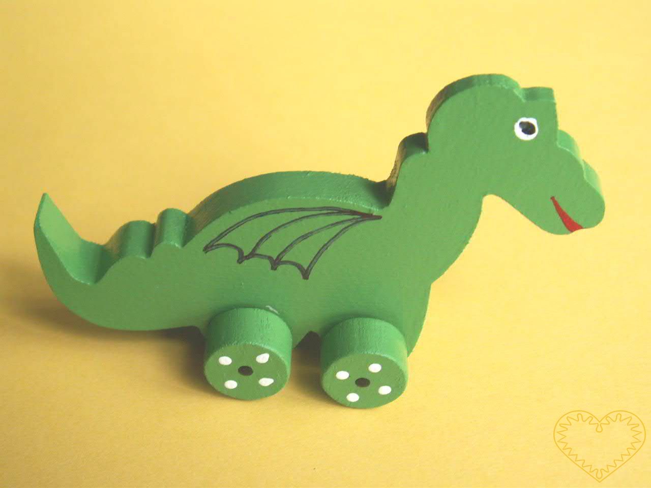 Malé vyřezávané zvířátko na kolečkách - dráček. Drobný malovaný suvenýr vycházející ze vzorů tradičních dětských dřevěných hraček.