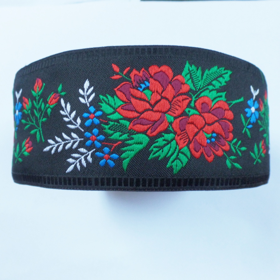 Černá krojová stuha s květinovým vzorem - vzorovka š 5,5 cm. Textilní tkaná stuha s vyšítým vzorem bílých, modrých a červených květů a zelených listů je vhodná zvláště k lemování tkanin a zdobení krojů, lze uplatnit v bytovém textilu.
