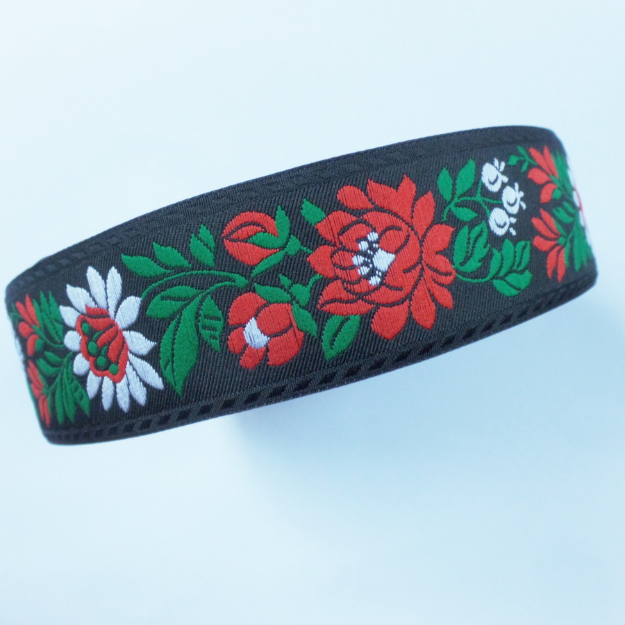 Černá krojová stuha s květinovým vzorem - vzorovka š 3,5 cm. Textilní tkaná stuha s vyšítým vzorem bílých a červených květů a zelených listů je vhodná zvláště k lemování tkanin a zdobení krojů, lze uplatnit v bytovém textilu.