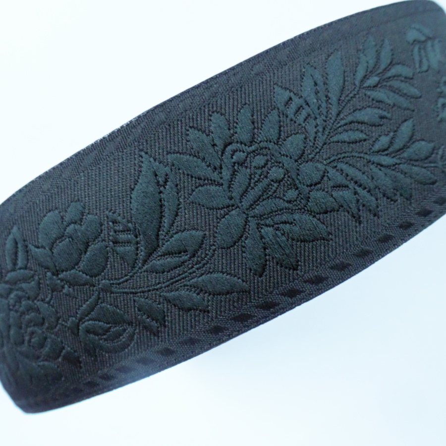 Černá krojová stuha s celočerným květinovým vzorem - vzorovka š 3,5 cm. Textilní tkaná stuha s vyšítým vzorem černých květů a listů je vhodná zvláště k lemování tkanin a zdobení krojů, lze uplatnit v bytovém textilu.