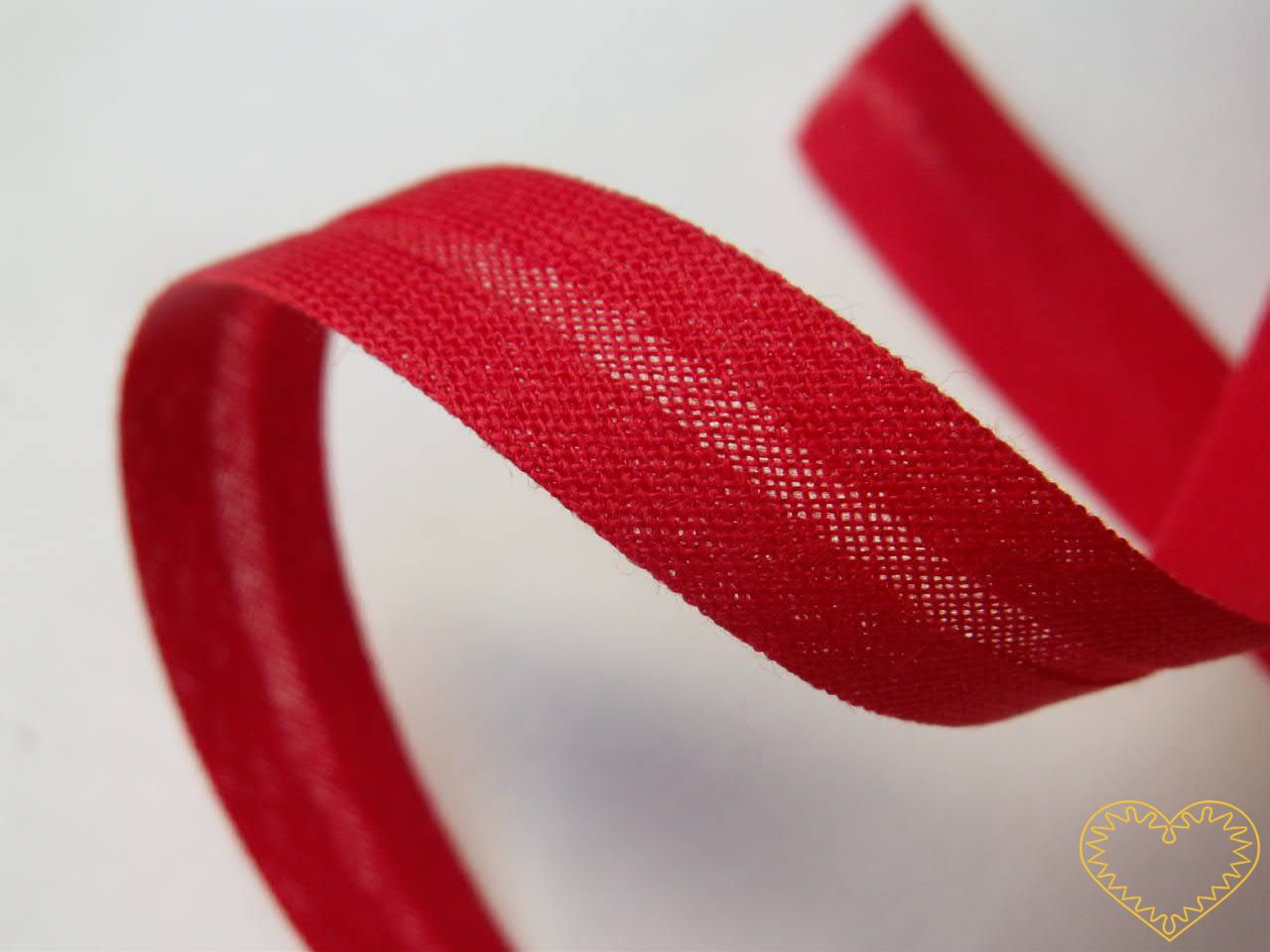 Šikmý proužek bavlněný červený, zažehlený z obou stran - šíře 1,4 cm. Varianta bílá a červená. Proužek je velmi vhodný na lemování jak bytového textilu (např. ubrusů, prostírání, polštářků, deček, chňapek), tak různých typů oděvů (např. trika, košile