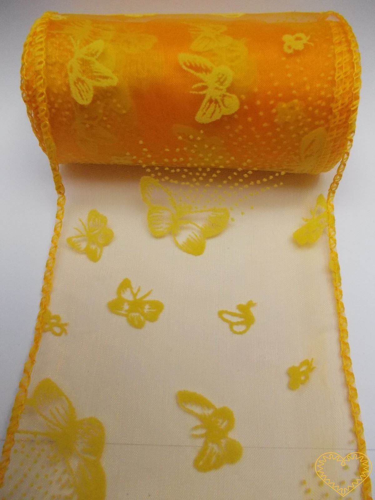Organza oranžová se žlutými motýly - šíře 10 cm, délka 9,14 m, z obou stran obroubená. Organza má široké využítí - k dekoračním účelům, k šití, do květinových aranžmá, pro výzdobu slavnostní tabule, k balení dárků, jako mašle, na výrobu broží i další